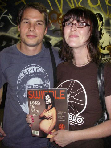 Two people hold up a Swindle magazine with Banksy on the cover.