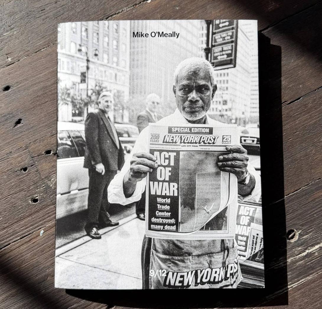 Cover of Mike O’Meally’s book 9/12: a black-and-white photo of a New York newspaper vendor holding up a New York Post with the headline ACT OF WAR.